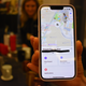 A person holding up a phone showing the Apple Find My feature and the person's mug.